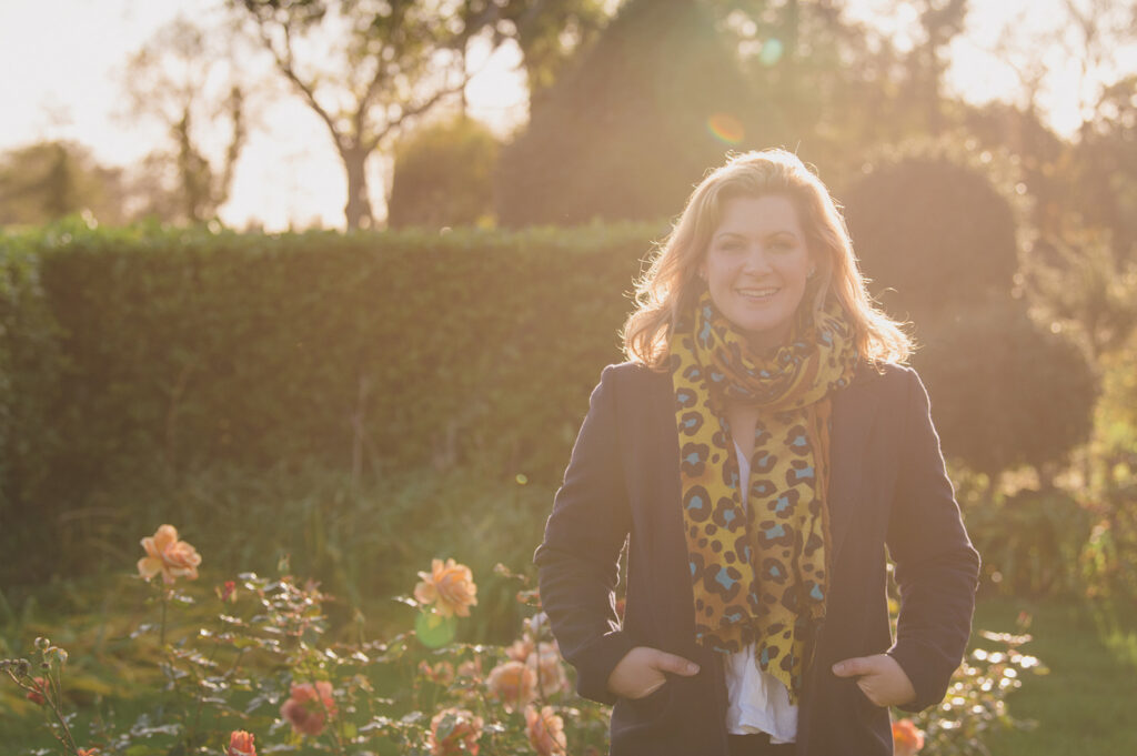 Natasha Spencer, wedding planner pictured in her garden at home with roses in the evening golden light