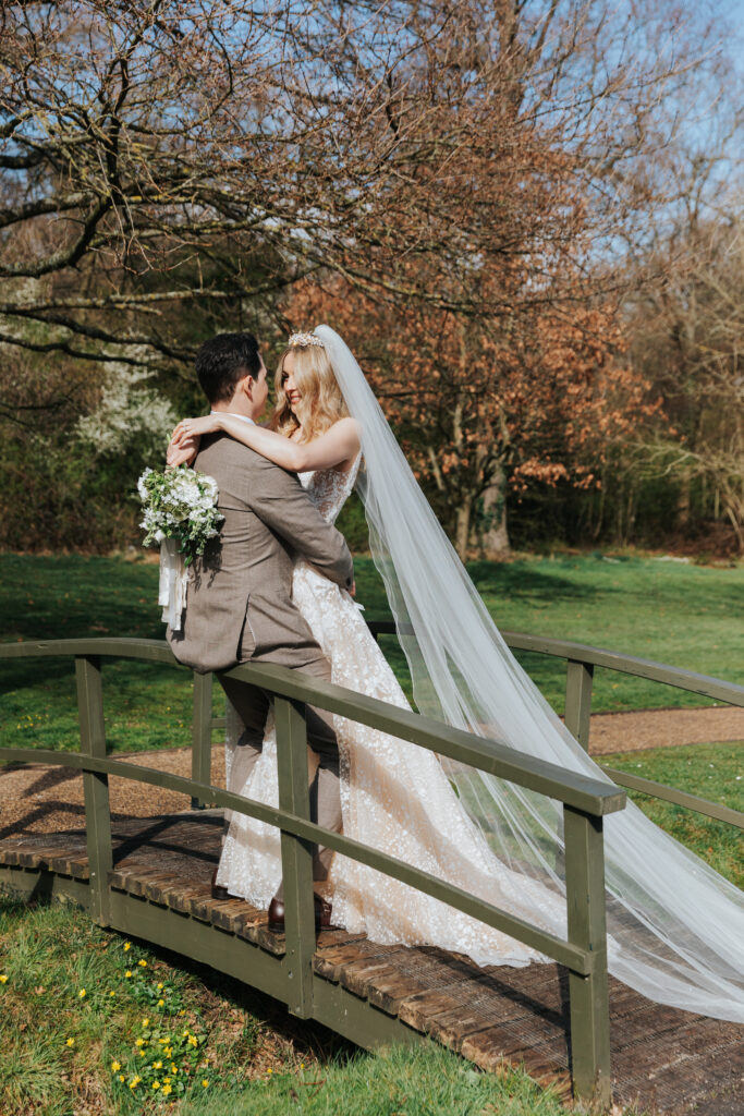 Freddie and Joscha on their wedding day posing in the spot where Joscha proposed at the couples old school in Hertfordshire