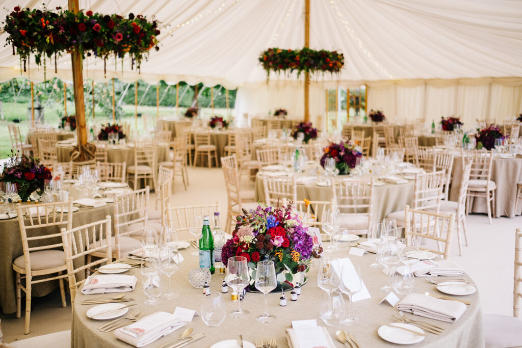 Inside a traditional marquee wedding with bold bright coloured florals. Planned by luxury marquee wedding planner Natasha Spencer Weddings & Events at a private home in Goudhurst, Kent.