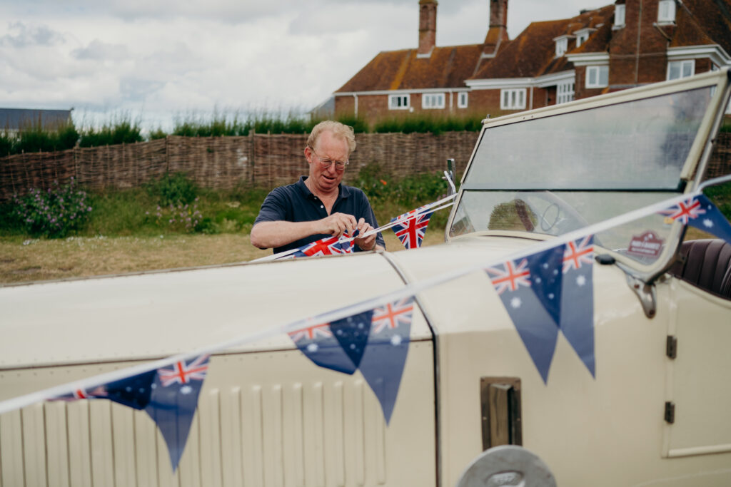 Father of the groom tying Union Jack and Australian bunting onto wedding car on the morning of the wedding.