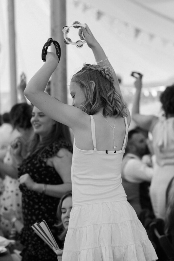 Flower Girl at a marquee wedding dancing with tambourines
