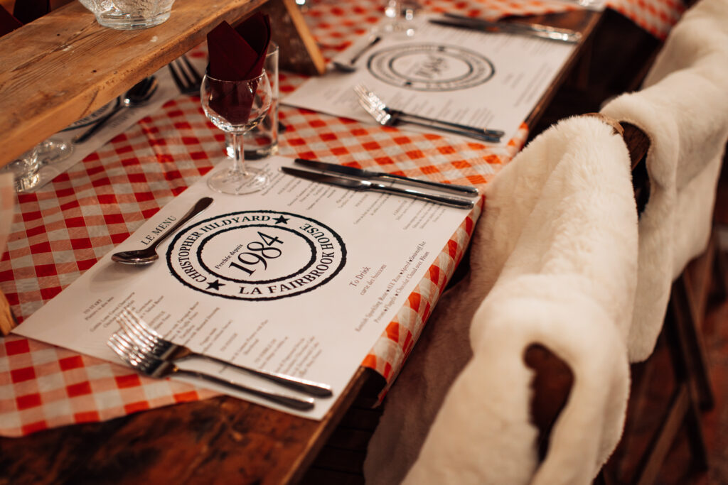 Close up of a table for a winter party with a personalised and branded place mat and red and which checked tabe cloth. 